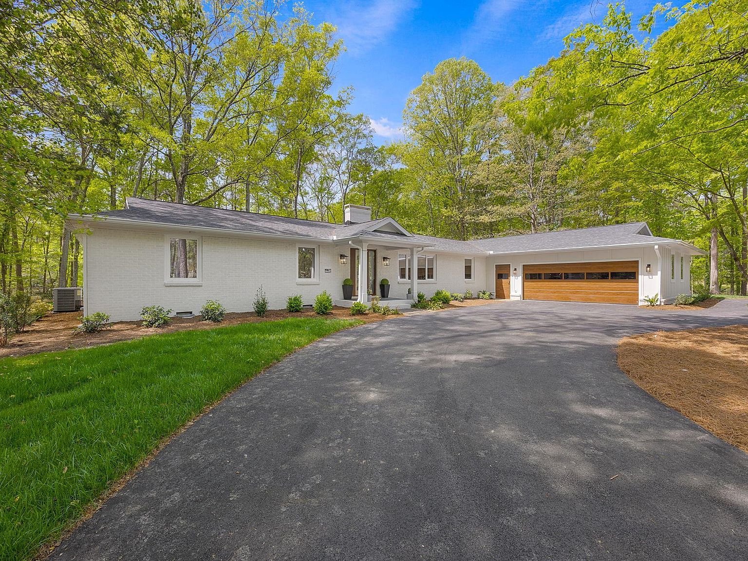 White-brick front elevation of 128 Edgecombe Rd in daylight, full house visible across a circular drive lined with pine forest