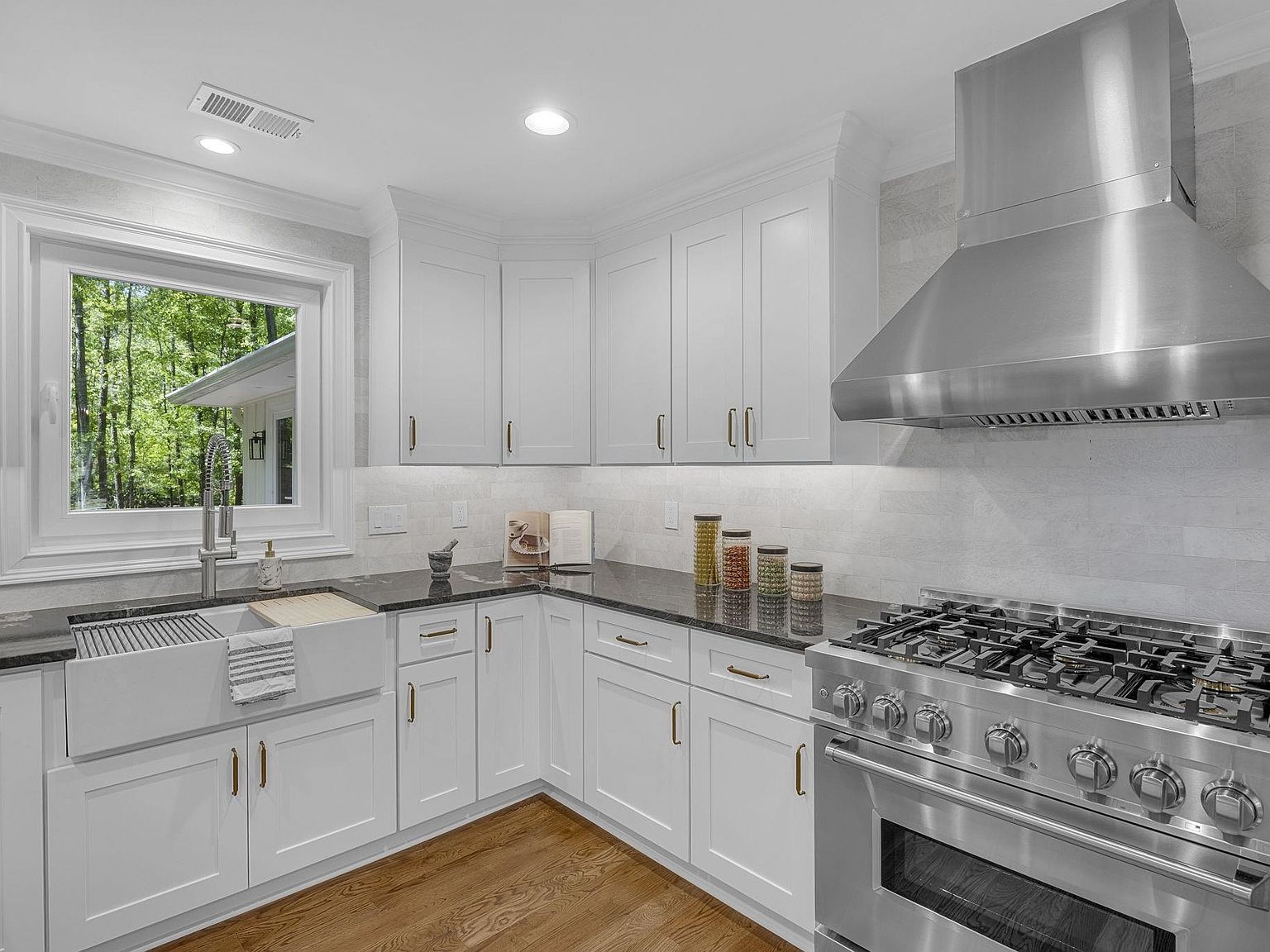 Close detail of the ZLINE gas range and brushed stainless hood against tile backsplash