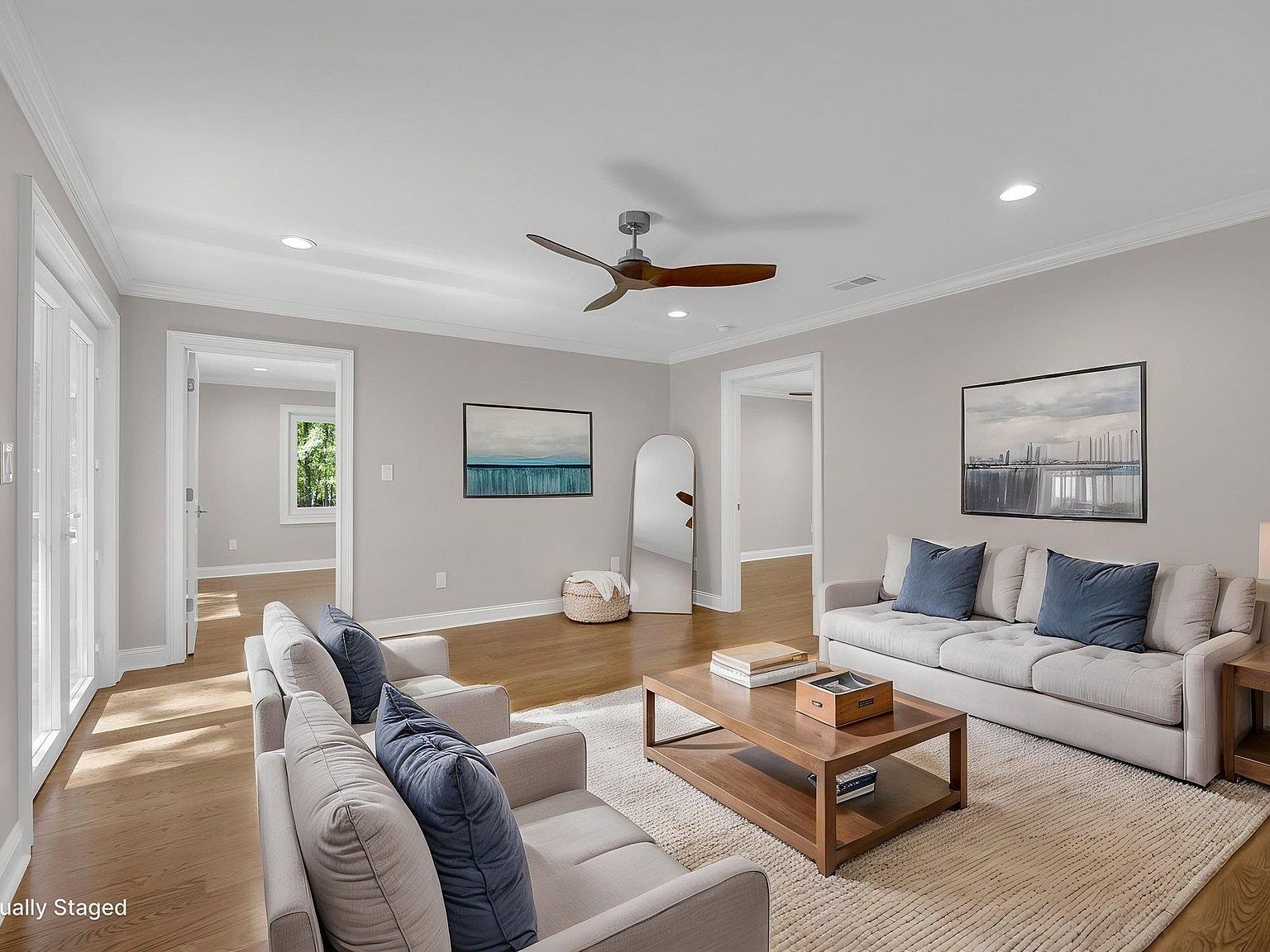 Bonus sitting room staged with twin sofas, blue accents, and walk-out doors to the wooded lot