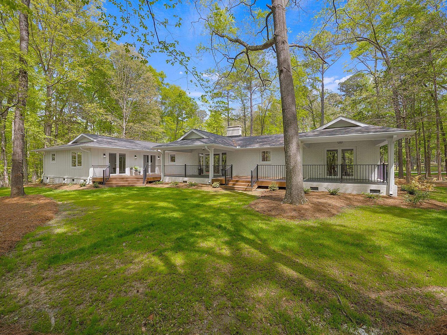 Rear elevation seen across the back lawn, full porch and deck spanning the length of the house