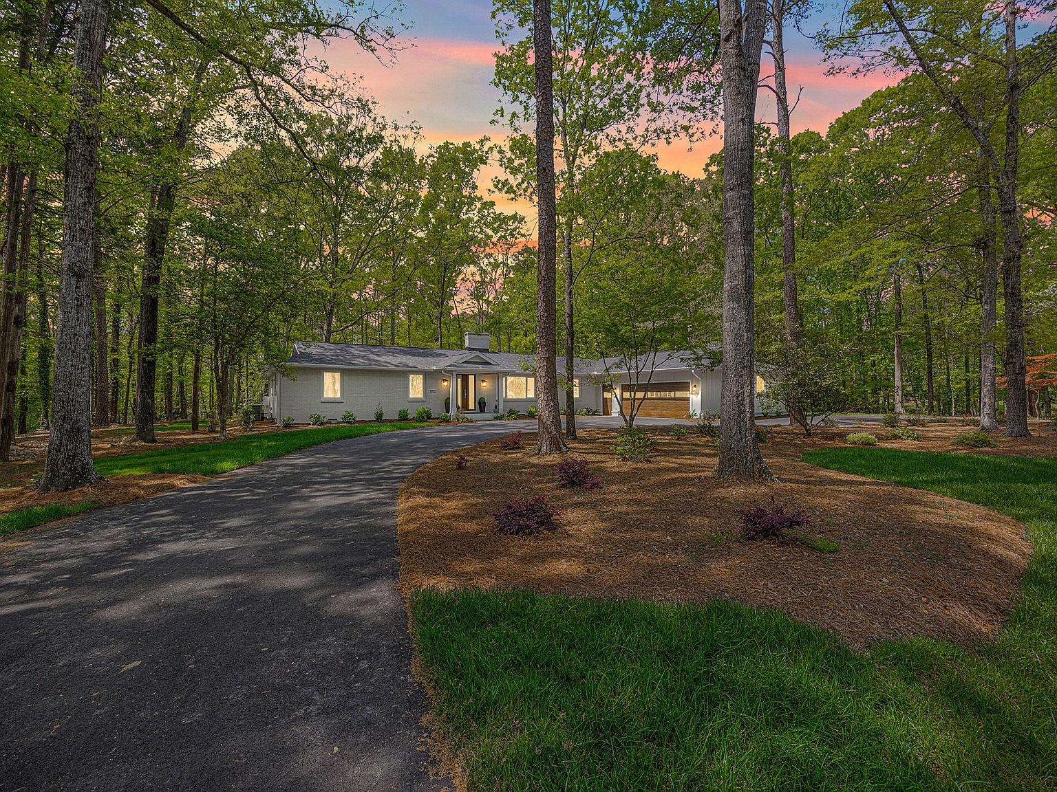128 Edgecombe Rd at dusk, white-brick ranch lit through pine trees at the end of a curved driveway